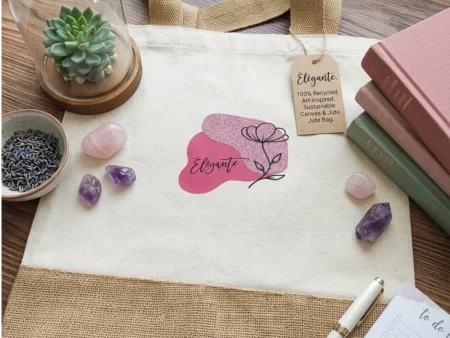Sac cabas toile et jute avec motif abstrait rosé pailleté et fleur, inscription "Élégante", dans un décor féminin et naturel.
