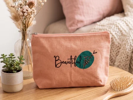 ochette en coton vieux rose avec motif "Beautiful" et galet vert pailleté posée sur un guéridon en bois.