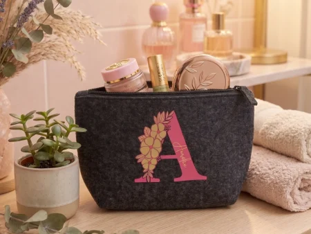 Pochette feutrine grise initiale A rose fleurie sur meuble en bois avec maquillage.