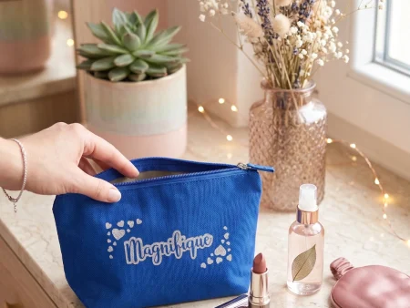 Pochette en coton bleu roi avec inscription "Magnifique" en paillettes argentées sur un meuble en bois clair.